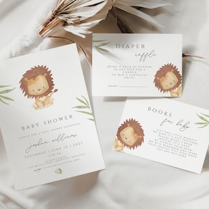 Puede incluir: Una invitación a una fiesta de bienvenida al bebé con una linda ilustración de un león. La invitación es para Joshua Williams y está programada para el sábado 10 de junio de 2021. También hay dos tarjetas, una para una rifa de pañales y otra para una solicitud de libros para el bebé.