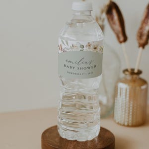 May include: A clear plastic water bottle with a green and white label that says "emilia's baby shower November 17, 2023".