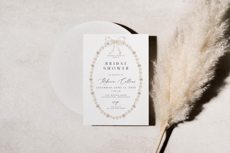 May include: A white bridal shower invitation featuring a pearl necklace design. The text reads "Please join us for a Bridal Shower in honour of Rebecca Collins, Saturday, June 11, 2022, 1:00 PM, The Round Barn, Lexington, Kentucky."
