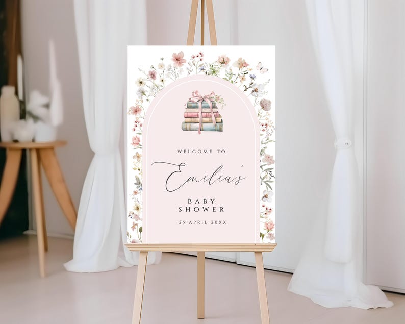 May include: A pink and white welcome sign with a floral border and a stack of books with a pink ribbon. The sign says "Welcome to Emilia's Baby Shower 25 April 20XX".