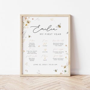 May include: A printable chart for a baby's first year milestones. The chart is decorated with floral illustrations and bees. It includes the baby's name, Emilia, and lists milestones such as height, weight, favorite foods, and first words. The chart is dated June 22, 2022, 10:25 AM.