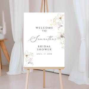 Puede incluir: Se&ntilde;al de bienvenida para una despedida de soltera con flores blancas y el texto "Bienvenida a la despedida de soltera de Samantha, 17 de abril de 20XX".