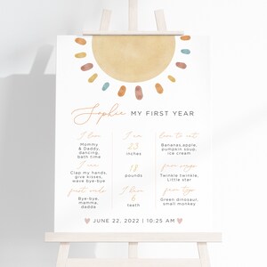 K&ouml;nnte beinhalten: Ein druckbarer Chart f&uuml;r die Meilensteine des ersten Lebensjahres eines Babys. Der Chart zeigt eine Aquarellsonne mit gelbem Hintergrund und bunten Punkten. Der Chart enth&auml;lt den Namen des Babys, Sophie, und listet Meilensteine wie Gr&ouml;&szlig;e, Gewicht und erste Worte auf. Der Chart enth&auml;lt auch ein Datum und eine Uhrzeit.