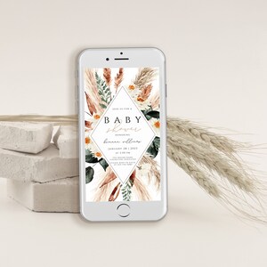 May include: A digital invitation for a baby shower with a watercolor design featuring pampas grass, flowers, and greenery. The text on the invitation reads "Join us for a Baby Shower Honoring [Name] January 28, 2023 at 2:00 PM".