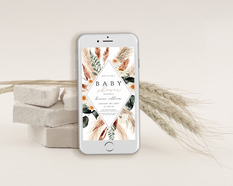 May include: A digital invitation for a baby shower with a watercolor design featuring pampas grass, flowers, and greenery. The text on the invitation reads "Join us for a Baby Shower Honoring [Name] January 28, 2023 at 2:00 PM".