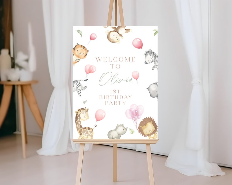 May include: Welcome to Olivia's 1st Birthday Party sign with a jungle animal theme. The sign features a giraffe, zebra, lion, monkey, and hippo with pink balloons.