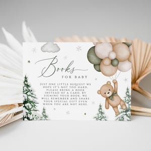May include: A baby shower invitation card with the text "Books for Baby". The card features a teddy bear holding balloons, pine trees, and a cloud illustration. The card is decorated with stars and snowflakes.