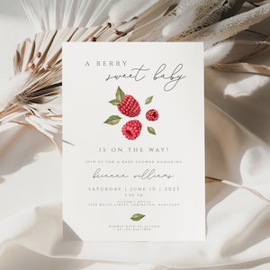 Puede incluir: Una invitación de baby shower blanca con una ilustración de acuarela de frambuesas rojas y hojas verdes. El texto dice "A berry sweet baby is on the way!" e incluye el nombre "Brianna Williams", la fecha "Saturday June 10, 2023", y la hora "1:00 PM".