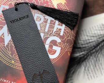 Marcapáginas de cuero negro con la inscripción "Violencia" y borla.