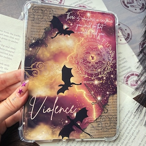 May include: A clear protective tablet case featuring a vibrant purple and orange nebula background with black silhouettes of three dragons, two swords, and gold line-art clouds. The text reads "There is nowhere in existence you could go that I wouldn't find you," "BASGIATH WAR COLLEGE," "DRAGON RIDER," and "Violence."