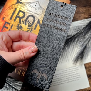 May include: Black leather bookmark with a dragon design and the text "MY HOUSE. MY CHAIR. MY WOMAN."