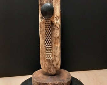 Majestically upright driftwood sculpture with subtly modern-looking appliqués, artistically expressed.