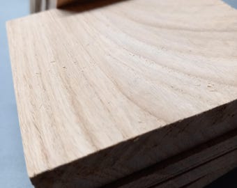 May include: A stack of light-colored wooden planks with visible wood grain. The planks are rectangular and appear to be freshly cut. The wood has a natural, unfinished look, with variations in color and texture.