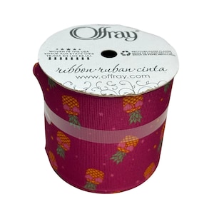 May include: A roll of Offray ribbon with a repeating pattern of yellow and orange pineapples on a dark pink background. The ribbon is wrapped around a white cardboard spool. The text "ribbon ruban cinta" is printed on the spool.