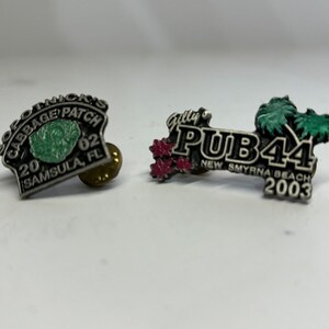 May include: Two vintage metal pins. One pin says "Sopotnick's Cabbage Patch 2002 Samsula, FL" with a green cabbage graphic. The other pin says "Gully's PUB44 New Smyrna Beach 2003" with palm tree graphics.