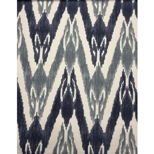 May include: Textile with a repeating chevron pattern in shades of navy blue, gray, and off-white. The design features a textured, ikat-style appearance, creating a visual interplay of color and form. The fabric's pattern is symmetrical and visually striking.