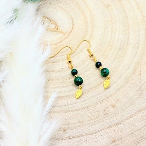 Peut inclure: Boucles d'oreilles dorées avec des perles de malachite vertes et des breloques en forme de feuilles dorées.