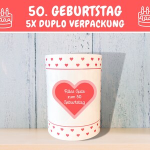 May include: White cylindrical container with a red heart design and the text "Alles Gute zum 50 Geburtstag". The container has a red heart with white polka dots on the front.