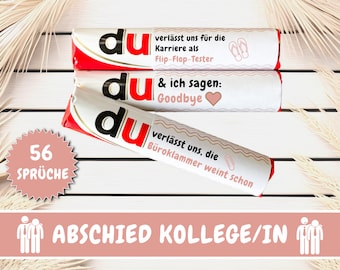 May include: Three red and white candy bar wrappers with the word "du" printed on them. The wrappers have different messages printed on them, including "Goodbye" and "Flip-Flop Tester". A pink circle with the text "56 Sprüche" is in the lower left corner. The background is a light wood surface.