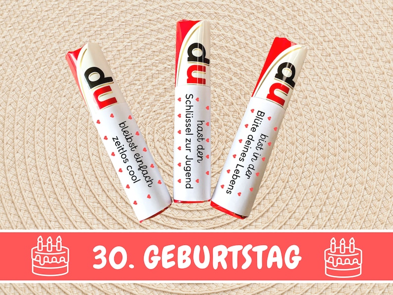 K&ouml;nnte beinhalten: Drei rote und wei&szlig;e Schokoladenriegel mit dem Wort "du" darauf. Jeder Riegel hat eine andere Botschaft. Die Botschaften sind "hast den Schl&uuml;ssel zur Jugend", "bleibst einfach zeitlos cool" und "bist in der Bl&uuml;te deines Lebens". Die Riegel sind in einer Reihe auf einem beigefarbenen Hintergrund angeordnet. Der Text "30. GEBURTSTAG" ist in roten Buchstaben unter den Riegeln geschrieben. Auf beiden Seiten des Textes befinden sich zwei wei&szlig;e Kuchen-Icons mit Kerzen.