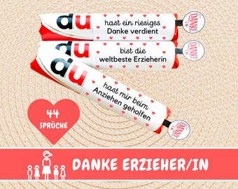 May include: Three white chocolate bars with red hearts and the text "du" on each bar. The bars have different messages on them, including "hast ein riesiges Danke verdient", "bist die weltbeste Erzieherin", and "hast mir beim Anziehen geholfen". There is a red heart with the text "44 SPRÜCHE" on it. The text "DANKE ERZIEHER/IN" is on a red banner with a white outline. There are five white stick figures on the banner, including one female stick figure in the middle.