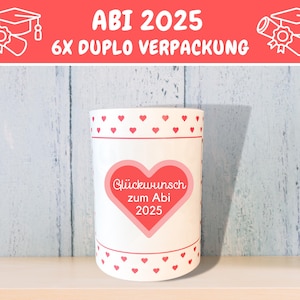 May include: White cylindrical container with a red heart design and the text "Gl&uuml;ckwunsch zum Abi 2025". The container has a red and white polka dot pattern around the top and bottom.