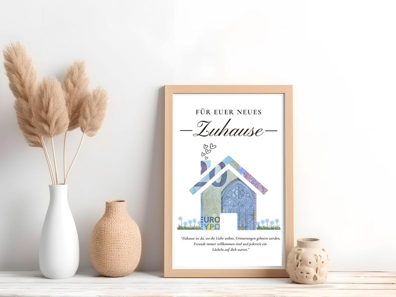 K&ouml;nnte beinhalten: Ein gerahmter Druck mit wei&szlig;em Hintergrund und einem hausf&ouml;rmigen Design aus einem Euro-Banknoten. Der Text "F&uuml;r euer neues Zuhause" befindet sich oben auf dem Druck. Das Zitat "Zuhause ist da, wo die Liebe wohnt, Erinnerungen geboren werden, Freunde immer willkommen sind und jederzeit ein L&auml;cheln auf dich wartet." befindet sich unten auf dem Druck.