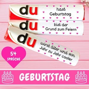 Puede incluir: Tres barras de chocolate blanco con corazones rosas y el texto "du" en cada barra. Las barras están apiladas una encima de la otra. La barra superior tiene el texto "hast Geburtstag", la barra del medio tiene el texto "bist der Grund zum Feiern", y la barra inferior tiene el texto "wirst älter und von Jahr zu Jahr cooler". Un corazón rosa con el texto "54 Sprüche" está debajo de las barras. El texto "GEBURTSTAG" está debajo del corazón. Dos iconos de pastel blanco con velas rosas están a cada lado del texto.