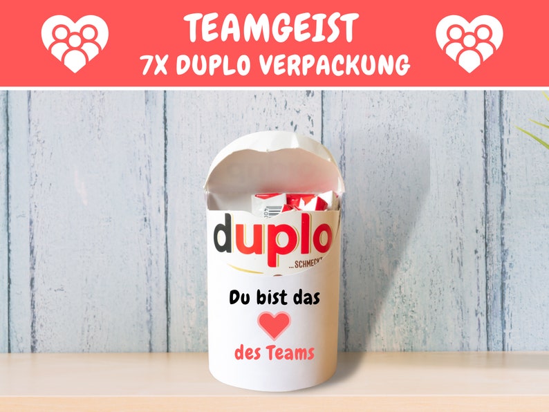 May include: White cylindrical container with a red heart and the text "Du bist das des Teams" (You are the one of the team). The container is filled with red and white Duplo building blocks. The container has the word "Duplo" printed on the side.
