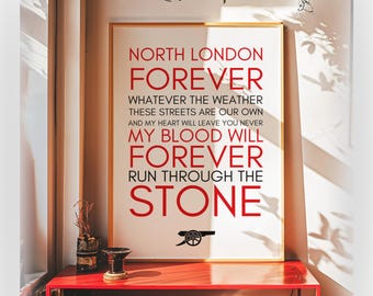 May include: A rectangular wall art print in a thin gold frame featuring red and black text on a white background. The text reads: NORTH LONDON FOREVER, WHATEVER THE WEATHER, THESE STREETS ARE OUR OWN, AND MY HEART WILL LEAVE YOU NEVER, MY BLOOD WILL FOREVER RUN THROUGH THE STONE, with a black cannon icon at the bottom.
