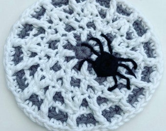 May include: A white and gray crocheted spider web with a black crocheted spider in the center.