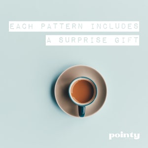 May include: A blue and white coffee cup with brown coffee inside, sitting on a beige saucer. The text "EACH PATTERN INCLUDES A SURPRISE GIFT" is above the cup.
