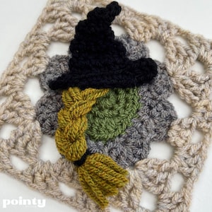 May include: A crocheted witch with a black hat, green face, and yellow braid and broom. The witch is set against a beige crocheted square background.