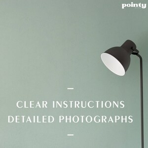 May include: A black lamp with a white shade against a light green wall. The text "CLEAR INSTRUCTIONS DETAILED PHOTOGRAPHS" is printed below the lamp.
