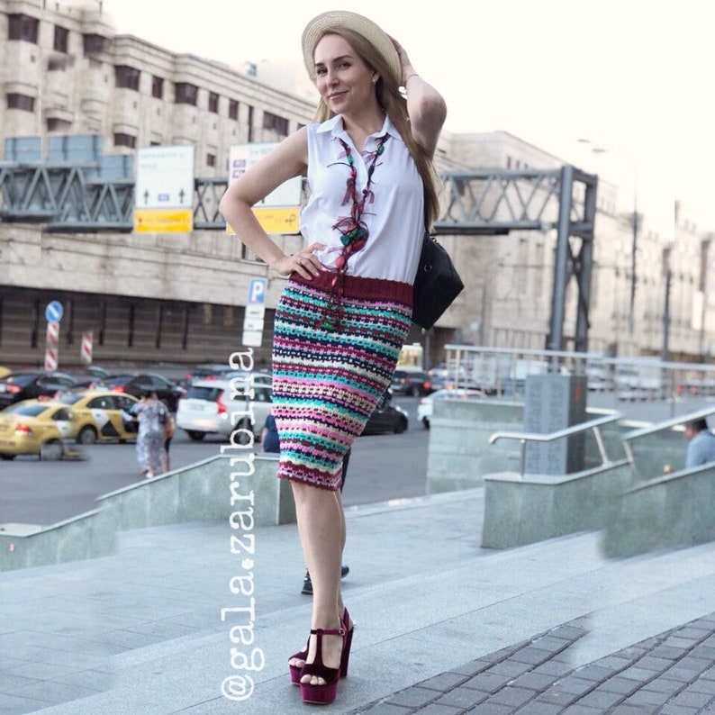 May include: A woman wearing a white sleeveless shirt, a colorful crocheted skirt, a straw hat, and burgundy heels. She is standing on a set of stairs in an urban setting. The text "@gala_zarubina" is visible in the lower left corner of the image.