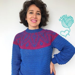 May include: A woman wearing a blue and pink crocheted sweater with a white background. The sweater has a geometric pattern on the top and a solid blue color on the bottom. The background has a drawing of a ball of yarn and a heart with the text "@GRACE_CROCHET".
