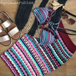 May include: A colorful striped crochet skirt with a black and tan woven tote bag, a striped bikini top, and a pair of gold sandals.