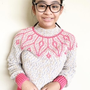 May include: A white and pink knitted sweater with a geometric pattern on the neckline and pink cuffs. The sweater has a speckled texture.