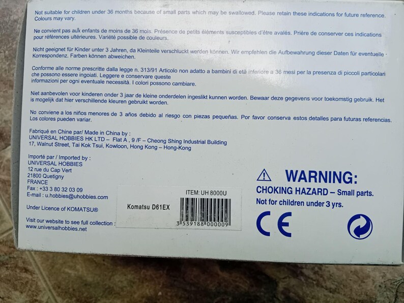 May include: A white box with blue text and a warning label. The box is for a Komatsu D61EX toy construction vehicle. The warning label reads "WARNING: CHOKING HAZARD - Small parts. Not for children under 3 yrs." The box also has a CE mark.