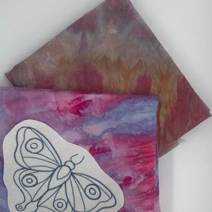 May include: Two pieces of fabric with a tie-dye pattern in shades of purple, pink, and brown. One piece has a butterfly embroidery design on it.