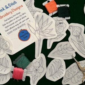 May include: Embroidery design kit featuring floral and leaf patterns. Includes pre-printed fabric patches, embroidery floss in orange, green, and pink, and a pair of gold scissors. The kit is from The Happy Hoop Studio.
