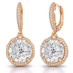 May include: A pair of rose gold earrings with a large, round, clear gemstone center, surrounded by smaller, clear stones. The earrings have a hinged hoop design and are set against a white background. The words "concept design" are in the bottom right corner.