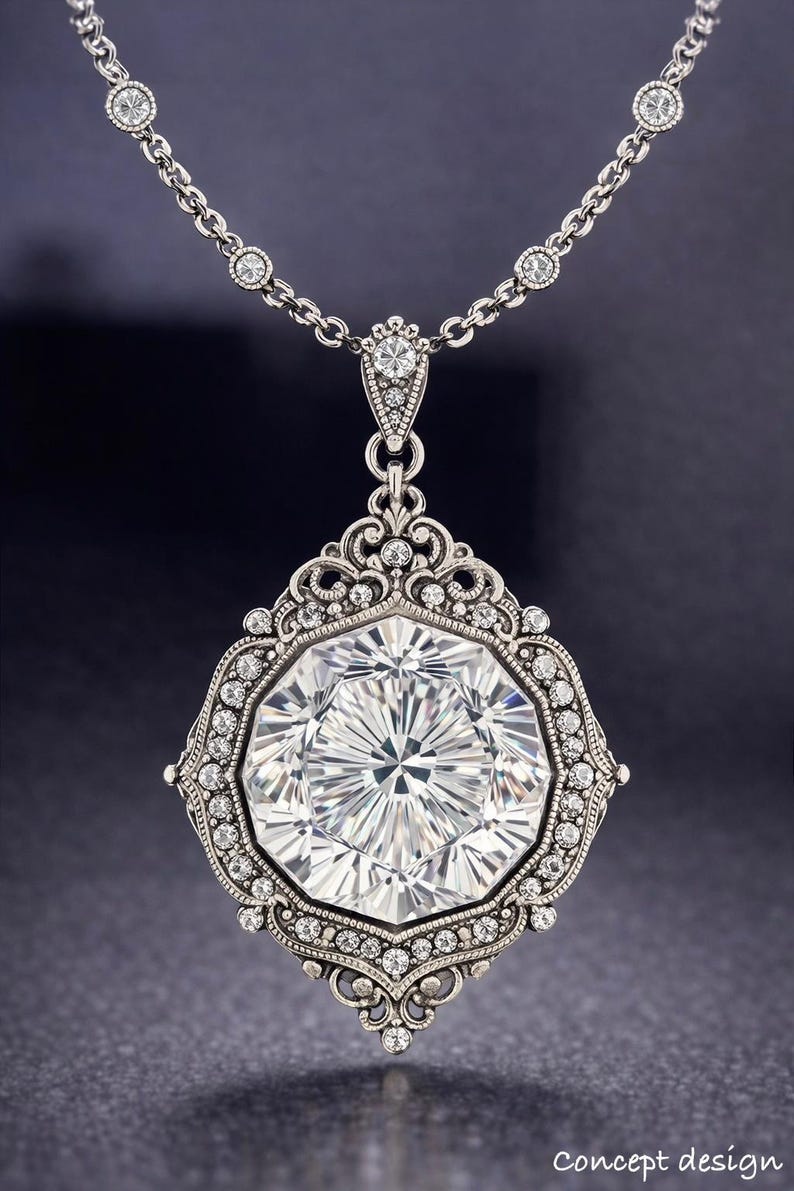 May include: A silver pendant necklace featuring a large, faceted, clear gemstone. The gemstone is surrounded by a decorative frame with smaller, clear gemstones. The necklace chain also has small, clear gemstones. The words "Concept design" are at the bottom.