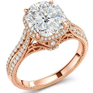 May include: Rose gold engagement ring featuring a large, square-cut diamond center stone surrounded by a halo of smaller diamonds. The band is adorned with intricate filigree and additional diamonds, creating a sparkling and elegant design. The ring is a concept design.
