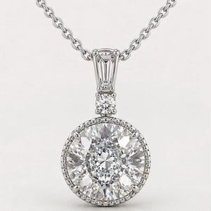 May include: A silver necklace featuring a large, round, clear gemstone pendant. The pendant is encircled by smaller stones and a beaded border. The necklace has a fine chain. The text "Concept Necklace Design" is at the bottom.