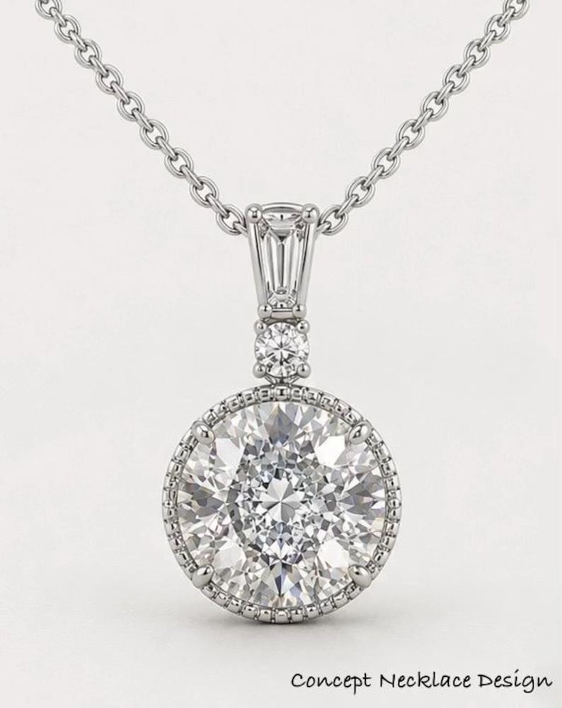 May include: A silver necklace featuring a large, round, clear gemstone pendant. The pendant is encircled by smaller stones and a beaded border. The necklace has a fine chain. The text "Concept Necklace Design" is at the bottom.