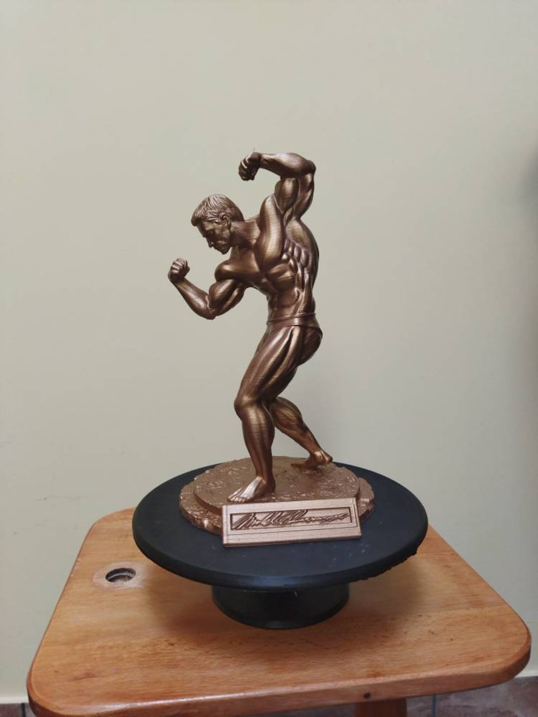 Arnold Schwarzenegger posando estatua en plataforma con firma Etsy España