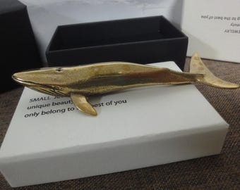 May include: A small, gold-colored whale sculpture on a white box with the text "SMALL JEWELRY unique beauty, only belong to the best of you".