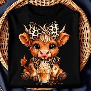Puede incluir: Sudadera negra con un ternero de dibujos animados con un lazo y bufanda con estampado de leopardo, sosteniendo una bebida de caf&eacute;. El ternero es marr&oacute;n y blanco con ojos grandes. Los granos de caf&eacute; est&aacute;n esparcidos alrededor de la bebida.