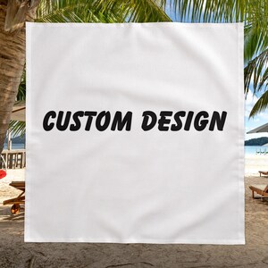 Puede incluir: Toalla de playa rectangular blanca con las palabras "CUSTOM DESIGN" en letras negras en negrita. La toalla está colgada de una palmera con una playa y el océano de fondo.